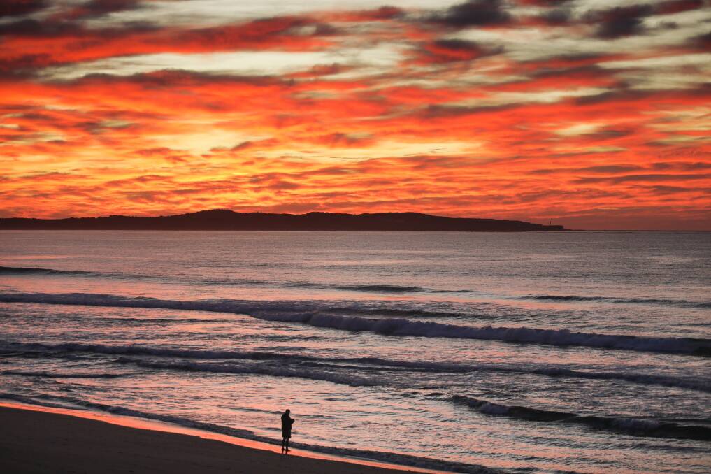 A lone figure marvels at nature's colours at North Cronulla Beach on Thursday. Picture by John Veage