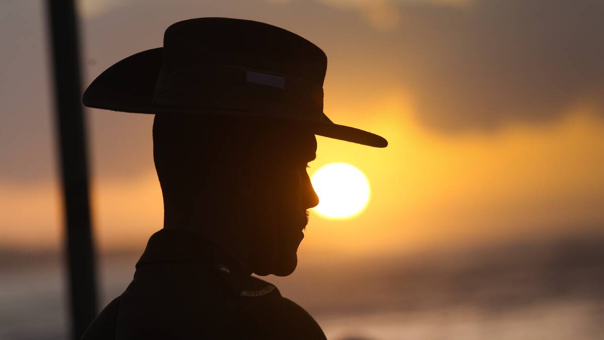 A soldier stands guard as the sun rises at Cronulla on Anzac day. Picture by John Veage
